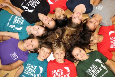 Schülerinnen und Schüler liegen im Kreis