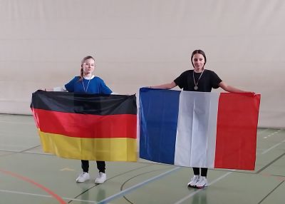 zwei Schülerinnen halten je eine französische und eine deutsche Fahne